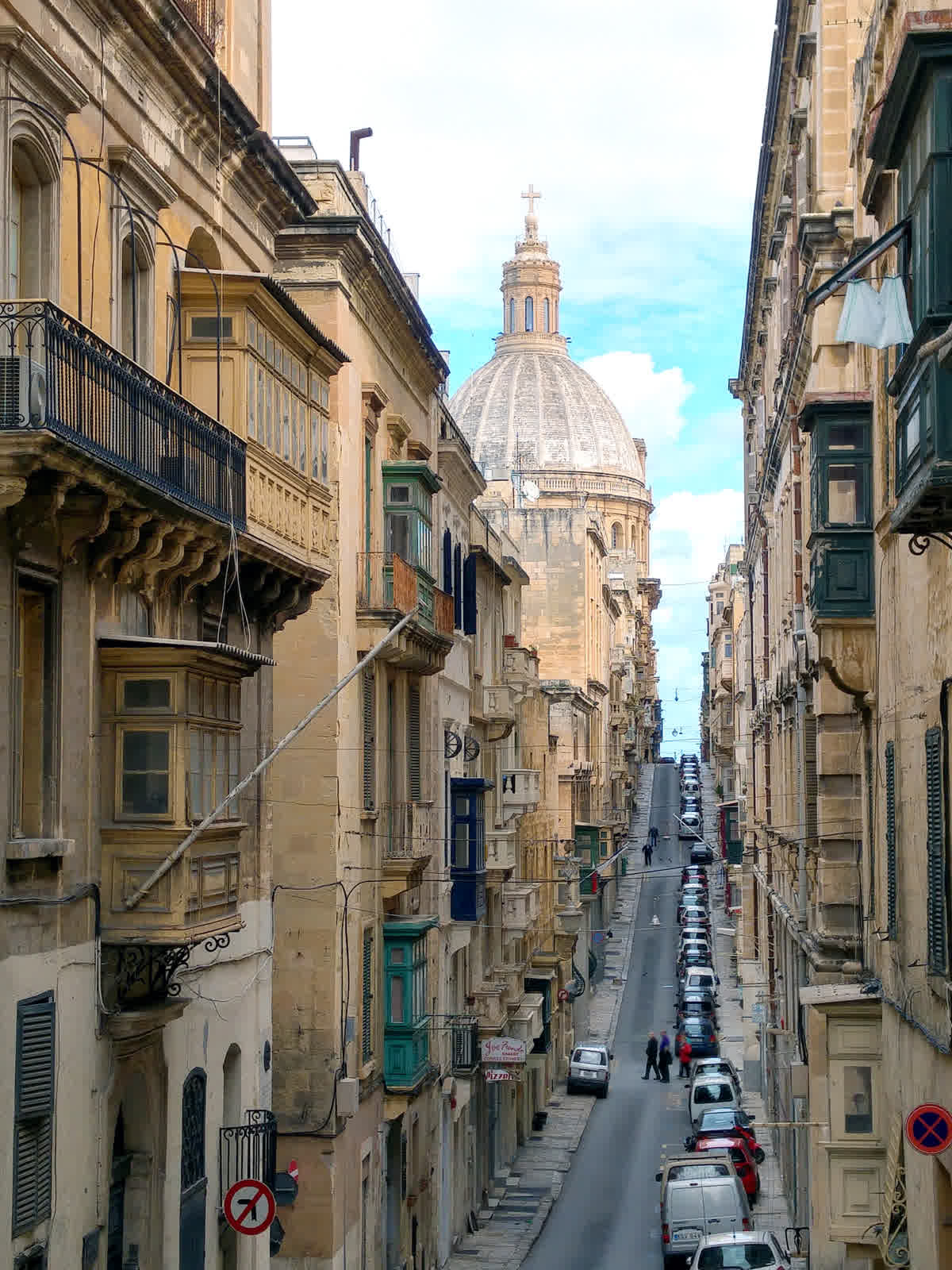 Old Mint Street in Valletta, a straight limestone street running toward the dome of the Basilica of Our Lady of Mount Carmel